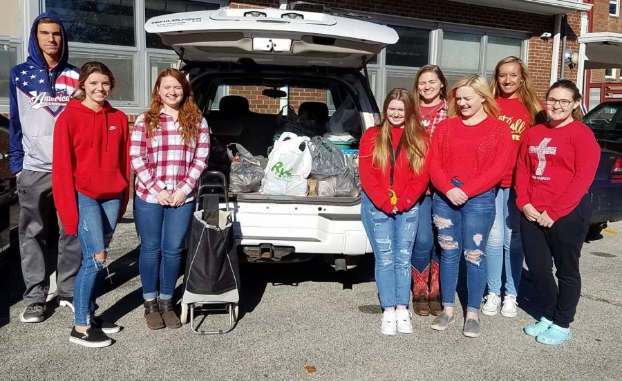 Pay It Forward members pose with canned items collected during the 2019 Trick or Treat for Cans Halloween night.