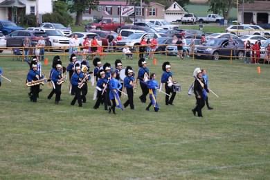 Oblong band and colorgaurd marching out to perform the national anthem. 